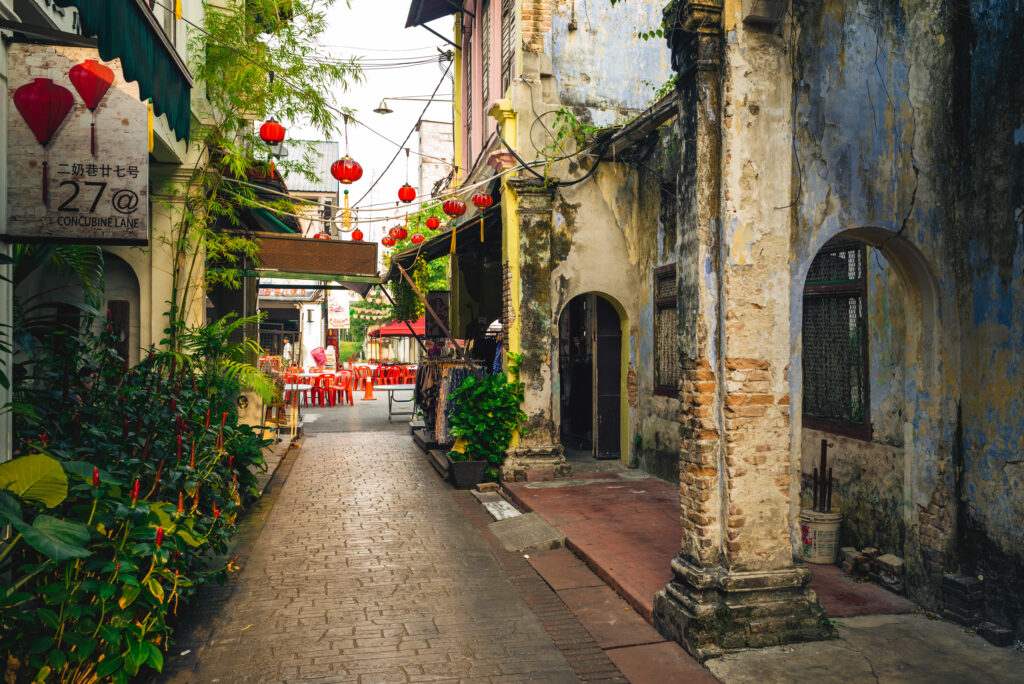 Concubine Lane Ipoh Malaysia with red lanterns, historic buildings, and market stalls in a narrow alleyway.